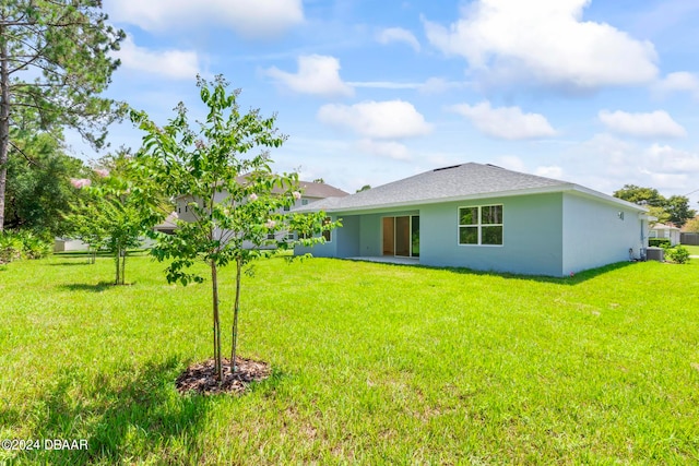 back of property featuring central AC and a yard