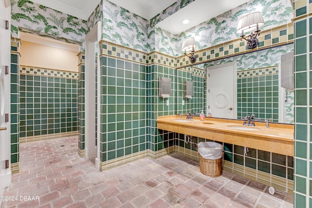 bathroom with tile walls, double sink, and crown molding