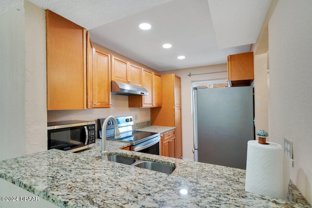 kitchen featuring kitchen peninsula, a textured ceiling, sink, light stone countertops, and appliances with stainless steel finishes