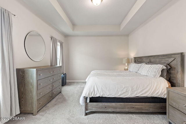 bedroom with a tray ceiling and light carpet