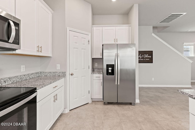 kitchen featuring light stone counters, white cabinets, stainless steel appliances, and light tile patterned floors