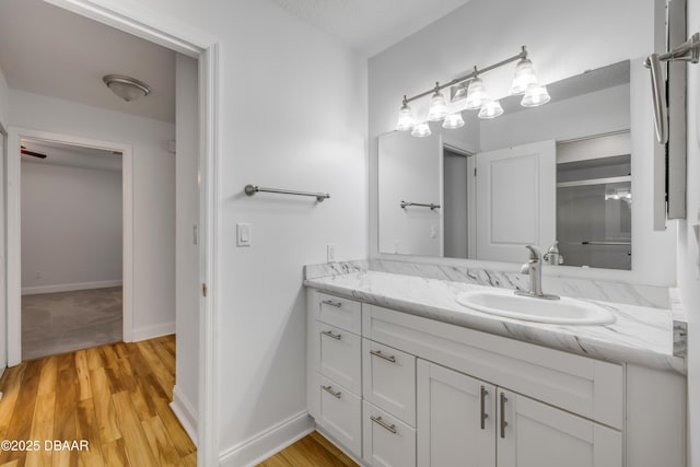 bathroom featuring vanity, wood finished floors, and baseboards