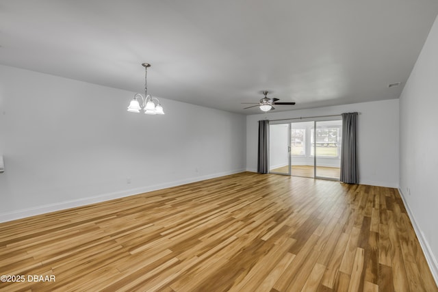 spare room featuring light wood-style floors, ceiling fan, baseboards, and a chandelier