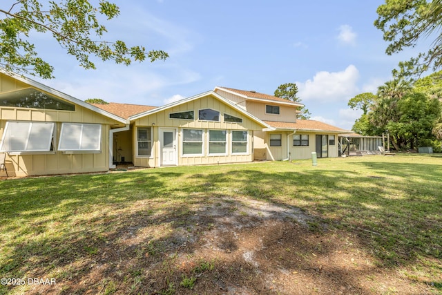 back of property featuring board and batten siding, a lawn, and roof with shingles