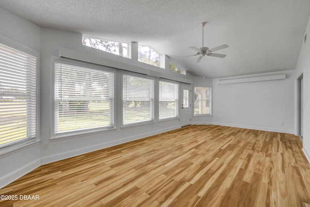 spare room featuring a ceiling fan, healthy amount of natural light, lofted ceiling, light wood-style flooring, and a textured ceiling