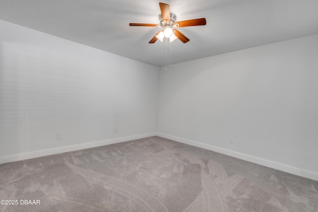 carpeted spare room featuring ceiling fan and baseboards