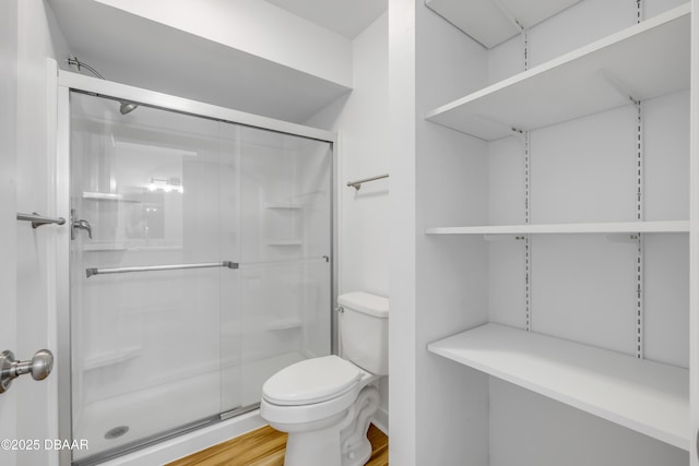 bathroom featuring toilet, a stall shower, and wood finished floors