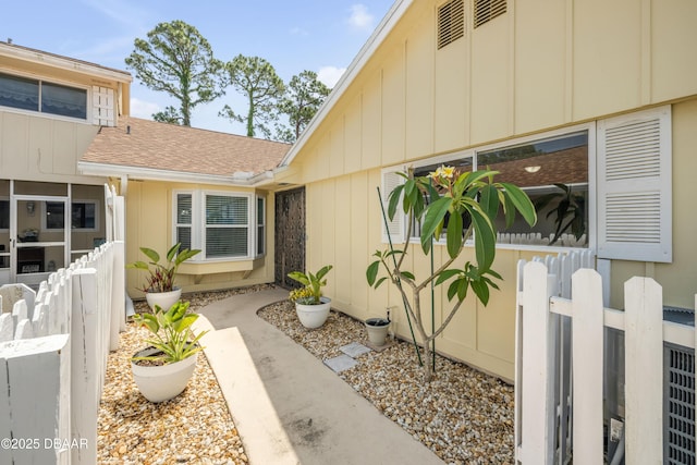 doorway to property with roof with shingles and fence