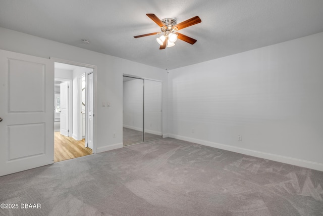 unfurnished bedroom featuring carpet, baseboards, a closet, and ceiling fan