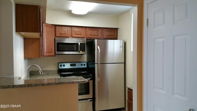 kitchen with appliances with stainless steel finishes, a textured ceiling, stone countertops, and sink