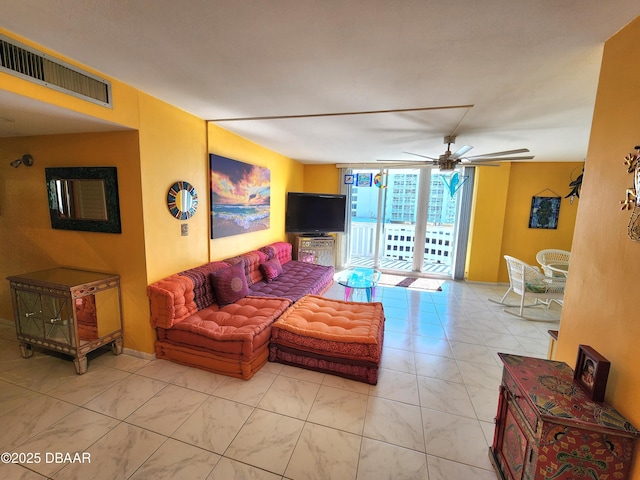 living room featuring ceiling fan and expansive windows