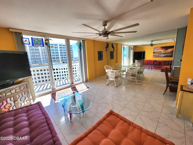 living room featuring ceiling fan and a wall of windows