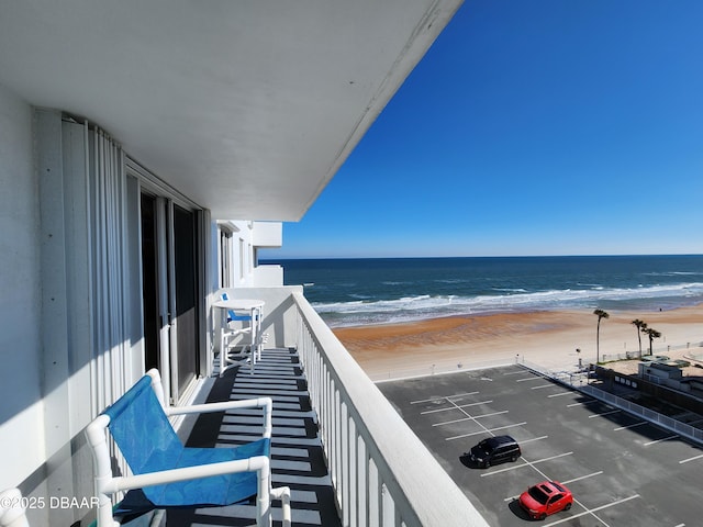 balcony with a water view and a view of the beach