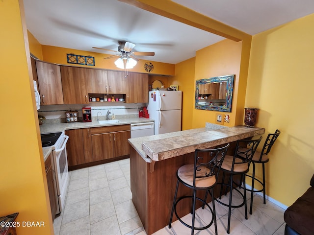 kitchen featuring kitchen peninsula, a kitchen breakfast bar, white appliances, and ceiling fan