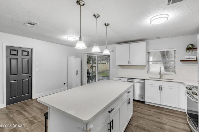 kitchen featuring sink, appliances with stainless steel finishes, a center island, a textured ceiling, and white cabinets