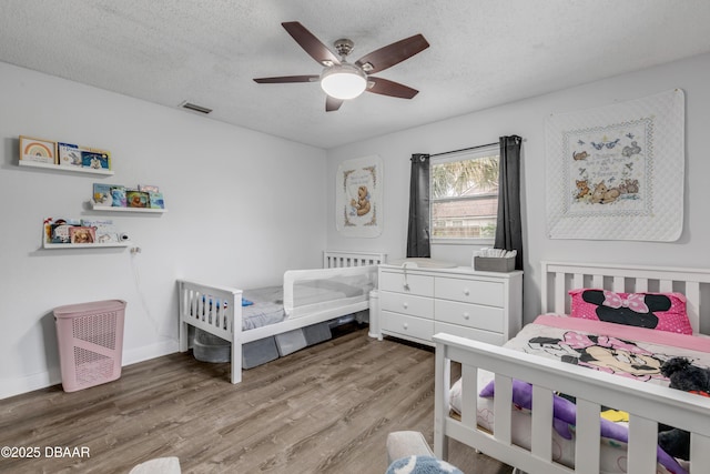 bedroom featuring ceiling fan, hardwood / wood-style floors, and a textured ceiling