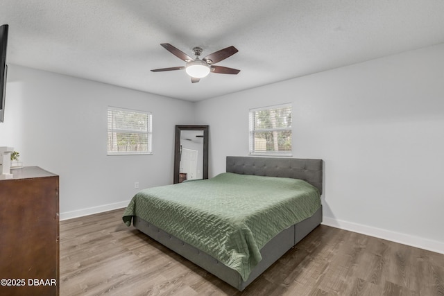 bedroom featuring multiple windows, hardwood / wood-style flooring, a textured ceiling, and ceiling fan