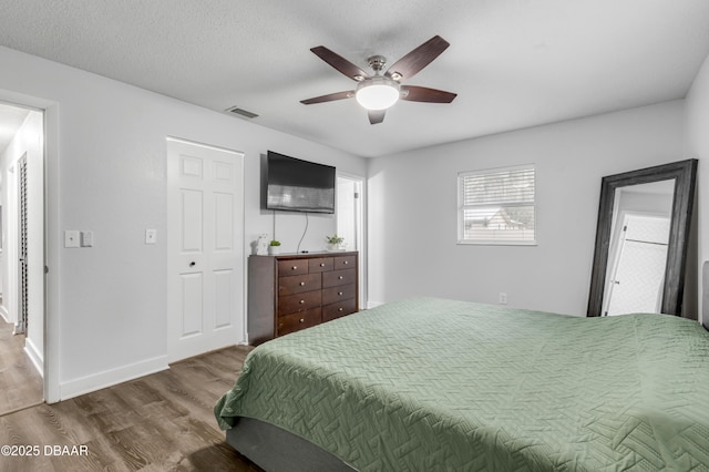 bedroom featuring hardwood / wood-style floors, a textured ceiling, and ceiling fan