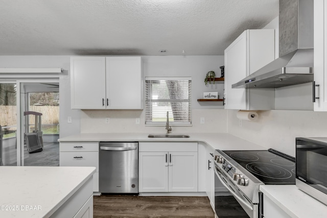 kitchen with wall chimney exhaust hood, sink, white cabinetry, a textured ceiling, and stainless steel appliances