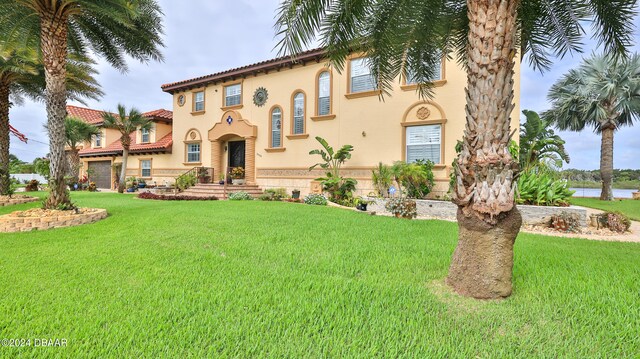 mediterranean / spanish house with a garage and a front lawn