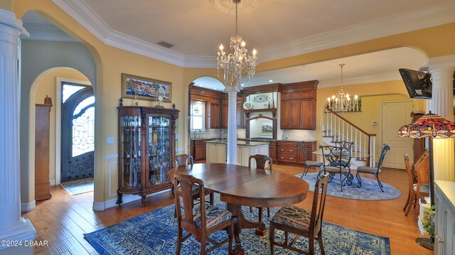 dining area featuring decorative columns, light hardwood / wood-style floors, and ornamental molding