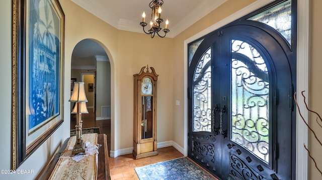 foyer entrance featuring light hardwood / wood-style floors, french doors, a notable chandelier, and ornamental molding