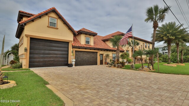 mediterranean / spanish-style home with a garage and a front lawn