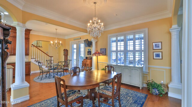 dining area featuring wood-type flooring, crown molding, and decorative columns