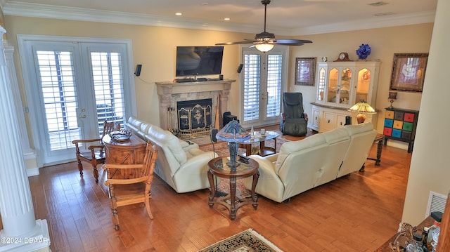 living room featuring crown molding, hardwood / wood-style flooring, ceiling fan, and a high end fireplace