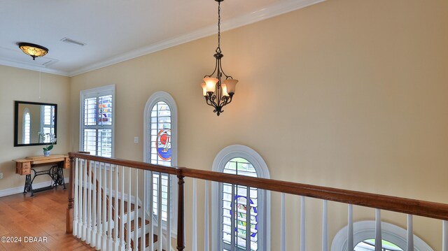 hall with ornamental molding, wood-type flooring, and a healthy amount of sunlight