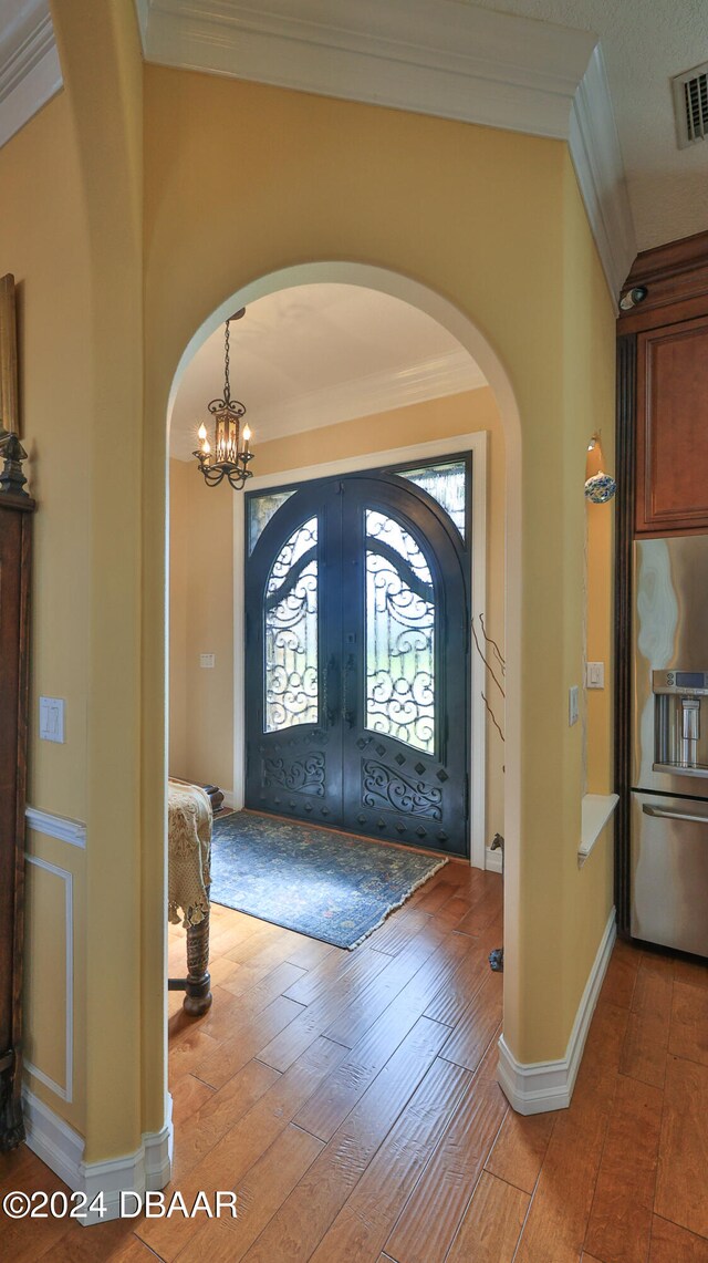 foyer entrance featuring french doors, light wood-type flooring, and crown molding