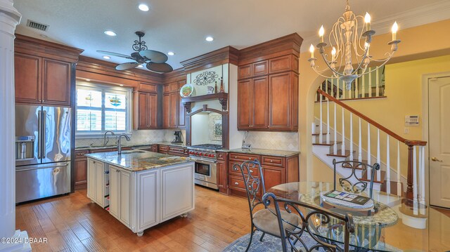 kitchen with high quality appliances, backsplash, light stone counters, and light hardwood / wood-style flooring