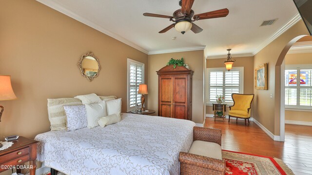 bedroom with ornamental molding, hardwood / wood-style flooring, and ceiling fan