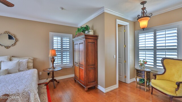 living area with a wealth of natural light, light hardwood / wood-style floors, and crown molding