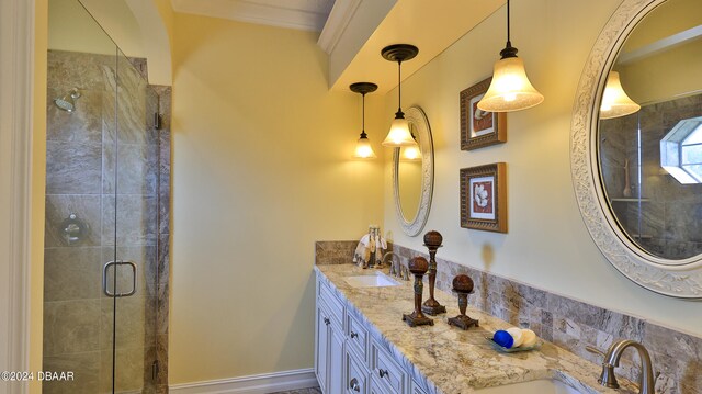 bathroom with a shower with shower door, vanity, and ornamental molding