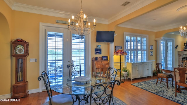 dining space featuring ornamental molding, wood-type flooring, and a chandelier