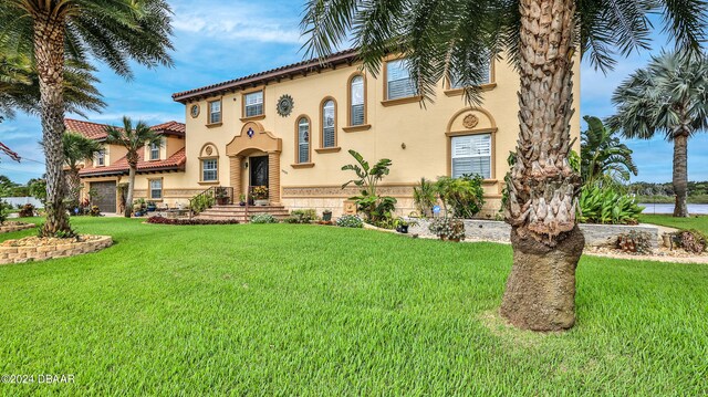 mediterranean / spanish home featuring a garage and a front yard