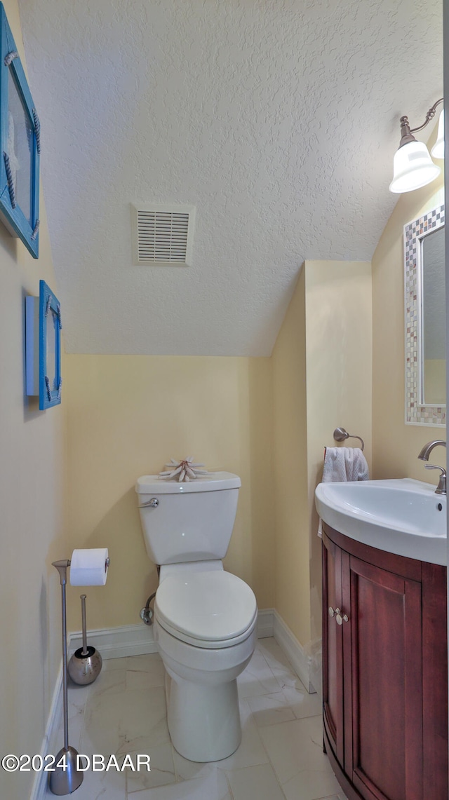 bathroom featuring vanity, a textured ceiling, and toilet