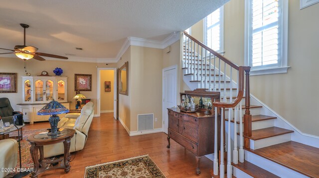 interior space featuring wood-type flooring, ceiling fan, and crown molding