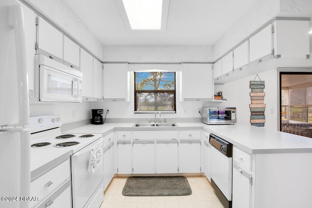 kitchen with white appliances, white cabinetry, sink, and kitchen peninsula