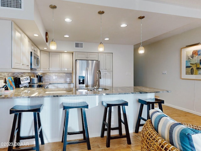 520 S Peninsula Ave Unit 2D7, New Smyrna Beach, FL 32169 - kitchen with white cabinetry, stainless steel appliances, hanging light fixtures, and light hardwood / wood-style flooring