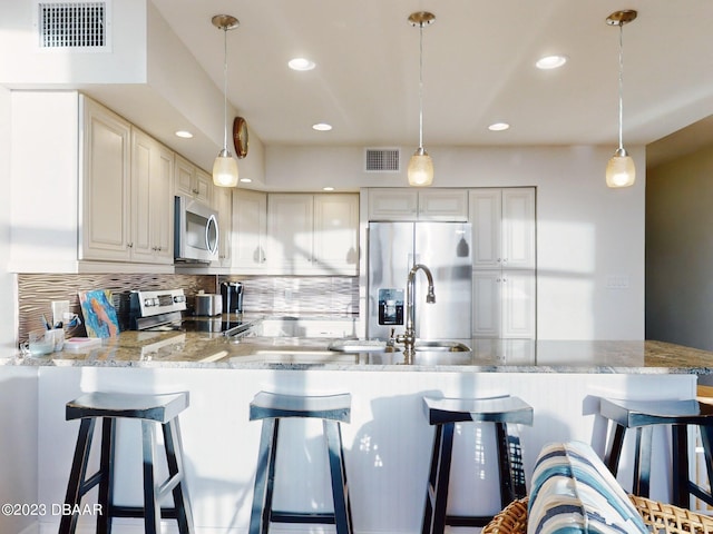 520 S Peninsula Ave Unit 2D7, New Smyrna Beach, FL 32169 - kitchen with white cabinetry, kitchen peninsula, stainless steel appliances, and decorative light fixtures