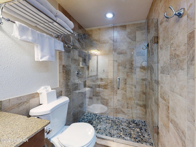 520 S Peninsula Ave Unit 2D7, New Smyrna Beach, FL 32169 - bathroom with toilet, vanity, a textured ceiling, and a shower with door