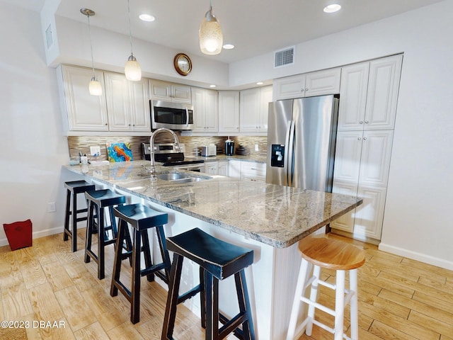 520 S Peninsula Ave Unit 2D7, New Smyrna Beach, FL 32169 - kitchen featuring stainless steel appliances, kitchen peninsula, a kitchen bar, decorative light fixtures, and white cabinets