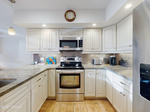 520 S Peninsula Ave Unit 2D7, New Smyrna Beach, FL 32169 - kitchen featuring light hardwood / wood-style floors, light stone counters, appliances with stainless steel finishes, white cabinets, and decorative backsplash