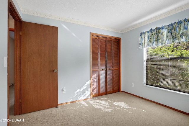 unfurnished bedroom featuring light colored carpet, a textured ceiling, and a closet