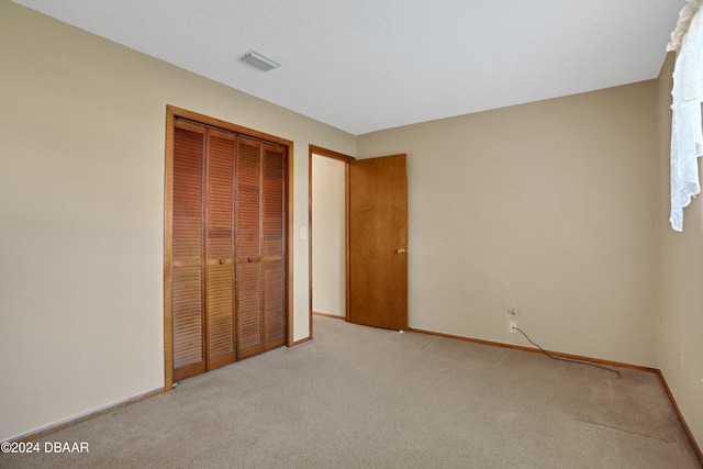 unfurnished bedroom with a closet and light carpet