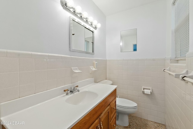 bathroom featuring vanity, toilet, and tile walls