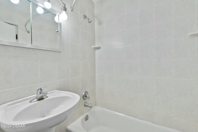 bathroom featuring tiled shower / bath, sink, and tile walls