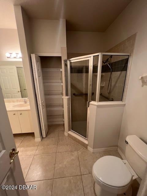 bathroom featuring tile patterned floors, vanity, toilet, and a shower with door